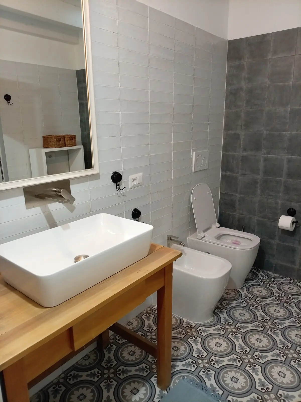 Il bagno privato con lavabo in legno e pavimento in cementine