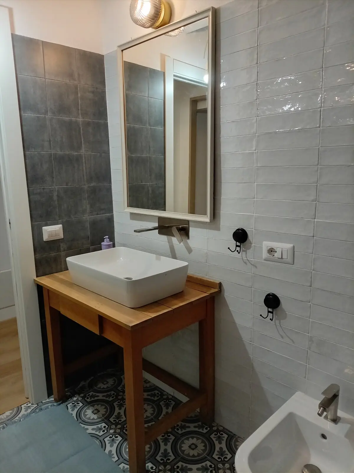 Il lavabo del bagno con lo specchio illuminato da un'applique